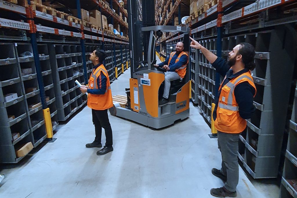 Two warehouse workers and one forklift driver using social distancing wearables