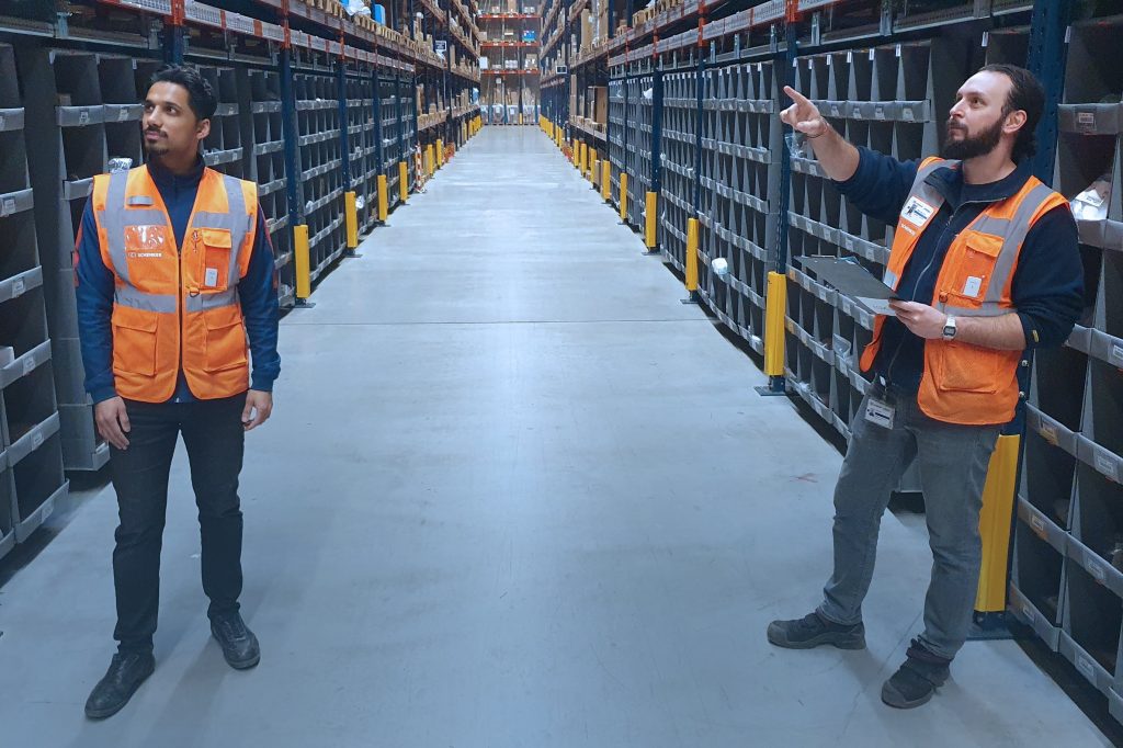 Two employees use social distancing wearables in logistics operations